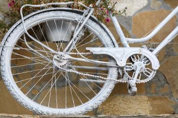 Detail of a bicycle painted white paint, standing against the wall. Rear wheel.