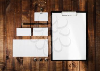Blank stationery set on wooden table background. Letterhead, business cards, badge, envelope and pencil. Top view.
