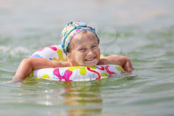 Happy child swims in the sea on inflatable ring on a clear sunny day. Shallow depth of field. Selective focus on the model's face.
