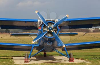 Blue single-engine biplane in retro style. Old airplane. Frontal view of the propeller engine and cockpit.