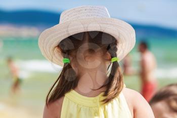 A child in a white hat admiring sea views. View from the back. Blurred background bokeh. Shallow depth of field. Selective focus. 