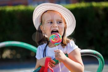 Little girl eating big candy. Shallow depth of field.