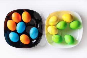 Easter eggs on black and white plates. Still life with easter eggs. Top view.