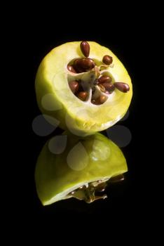 Quince cut in half with seeds on a black background with reflection. Vertical shot.
