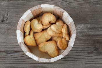 Heart shaped cookies in a wooden container on wooden background. Top view.
