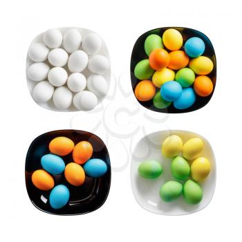 Four square plates with painted colorful Easter eggs. Colored eggs on a black and white dishes. Isolated on white background. Top view.