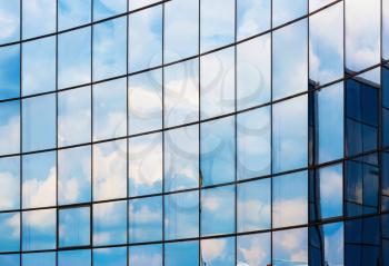 Facade of a modern office building. Modern industrial building with glass. Reflection of blue sky with clouds in the windows.