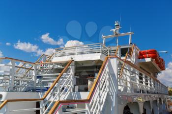 Close-up fragment of the deck with stairs white cruise ship on a background of blue sky with clouds.