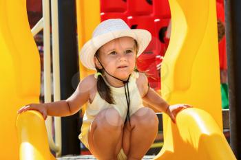 Portrait of a baby in a white hat and a yellow t-shirt on the playground on a sunny day. Shallow depth of field. Focus on model.