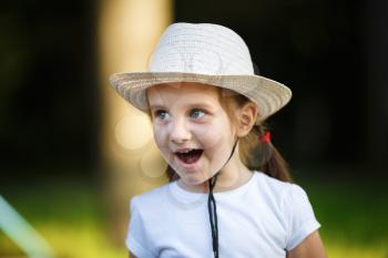 Happy baby girl in white hat outdoors. Shallow depth of field. Selective focus.