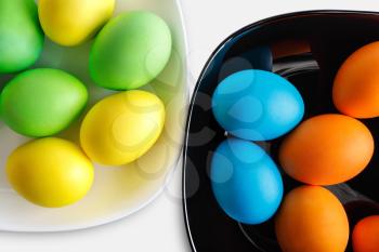 Colorful easter eggs on a black and white plates.