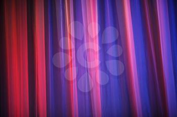 Purple theater curtain. Abstract purple background. Closeup of a theater curtain. Curtains theater lit by bright light of spotlights.