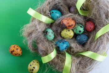 Easter eggs in a nest made of linen with satin ribbon. Quail eggs. Top view.