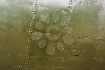 A fragment of the old airplane close-up. Abstract military green metal plates background texture with seams and rivets