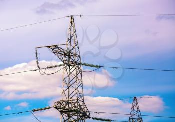 Electric pylon with cables against a bright evening sky. High voltage tower. Electricity wires.
