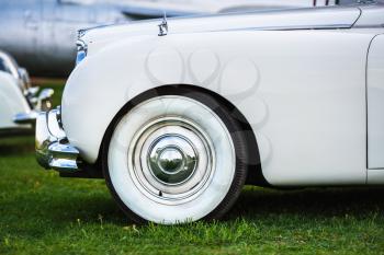 Close-up of the front part of the old white retro car. Fender and the front wheel of the car. White vintage car. Side view. Selective focus.