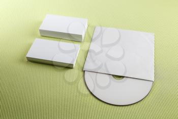 Photo of blank business cards and CD on a green background. Template for branding identity.