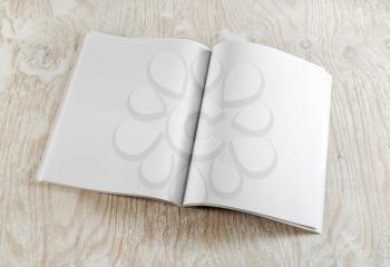 Blank opened book on light wooden background with soft shadows. Template for graphic designers portfolios. Top view.
