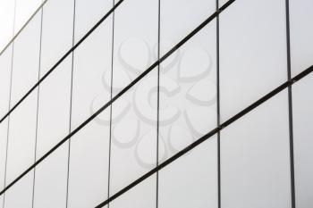 Close-up of a wall of a modern building decorated with square metal plates. Shallow depth of field. Selective focus.