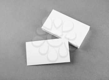 Photo of blank business cards on gray background. Mock-up for branding identity. For design presentations and portfolios. Top view. Grayscale image.