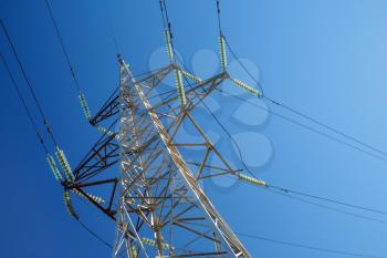 High-voltage electricity pylon against blue sky. Electric power transmission.
