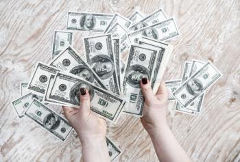Dollars in hands. Cash in hands. Fake money in hands. Money in female hands on light wooden background.