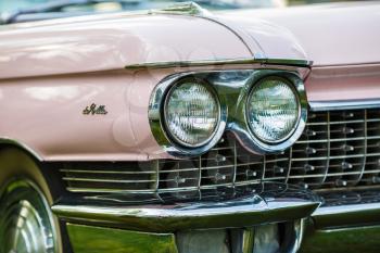 MINSK, BELARUS - MAY 07, 2016: Close-up photo of pink Cadillac de Ville. Detail on the headlight of vintage classic car. Selective focus.