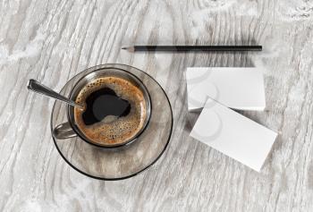 Coffee cup, business cards and a pencil on light wooden table background. Blank objects for placing your design. Top view.