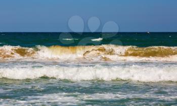 Ocean waves rolls ashore. Sea surf on a clear sunny summer day. Sea waves with foam and spray rolling ashore. Shallow depth of field. Selective focus.