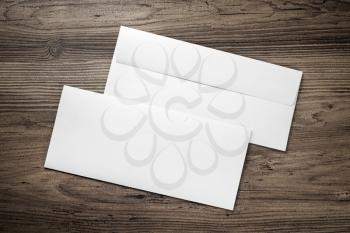 Photo of two blank envelopes on a dark wooden table background. Front and back side. Template for branding identity. Top view.