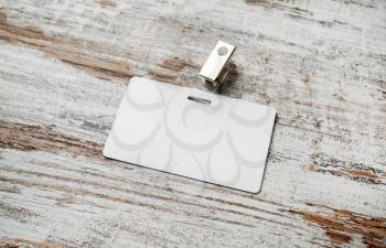 Blank white plastic badge on vintage wooden table background. Blank plastic id card. Selective focus. Top view.