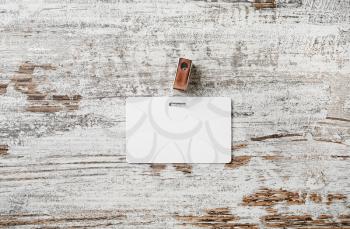 Photo of blank white plastic badge on vintage wooden table background. Blank plastic id card. Top view.