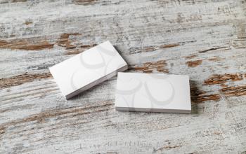 Mockup of two piles of blank horizontal business cards at wooden table background.