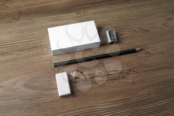Photo of blank business cards, pencil, eraser and sharpener on wooden background. ID template. Mockup for branding identity for designers. Top view.