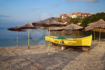 Nesebar, Bulgaria - September 05, 2014: Rescue boat and straw beach umbrellas and on a pebble beach. Seaside resort and ancient old town Nesebar in Bulgaria. Back Sea Coast.