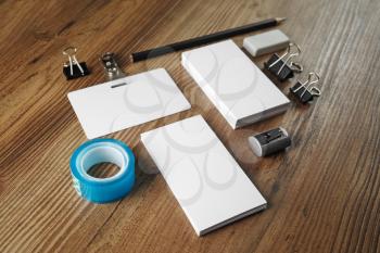 Photo of blank business cards, scotch tape, pencil, eraser, badge and sharpener on wood table background. Blank stationery for placing your design.