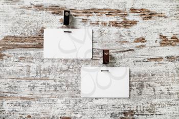 Two blank white badges on wooden table background. Responsive design mockup. Top view.