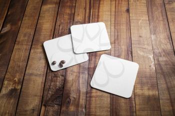 Blank square  coasters and coffee beans on vintage wood table background. Responsive design mockup.