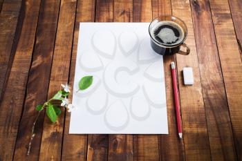 Photo of blank sheet of paper, coffee cup, pencil and eraser on wooden background with plenty of copy space. Blank template for placing your design. Responsive design mockup.