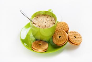 Green coffee cup, saucer, spoon and tasty cookies
