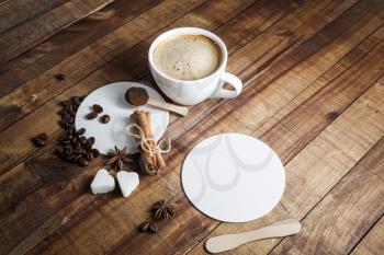 Fresh tasty coffee on vintage wooden kitchen table background. Coffee cup with cinnamon sticks, coffee beans, anise, sugar, spoon and coasters. Top view.