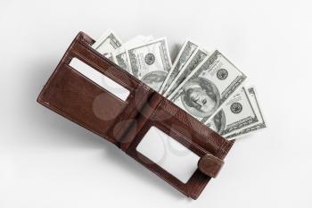 Dollars in a leather wallet on paper background. One hundred dollar bills. Top view.