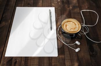 Photo of blank stationery on vintage wooden table background. Blank letterhead, coffee cup, headphones and pen. Blank branding template. Mock up for placing your design. Top view.