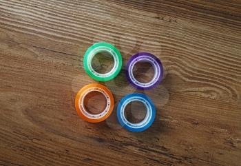 Four rolls of colorful scotch tape on wooden table background.