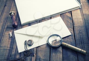 Blank paper envelope, magnifier, stamp and clock on vintage wood table background. Template for placing your design. Stationery elements. Postal accessories.