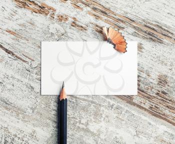 Blank business card and pencil on vintage wooden background. Stationery and ID mock up. Top view.