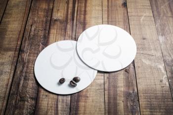 Photo of two blank white beer coasters on vintage wooden table background. Responsive design mockup. Template for your design.