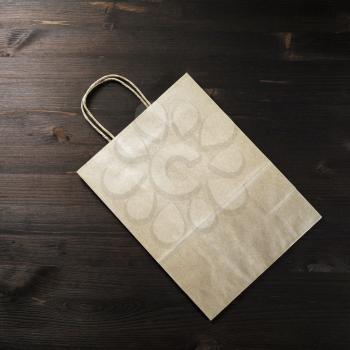 Blank craft paper bag on wood table background. Flat lay.