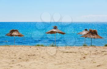 Thatched beach umbrellas. Blue sea and clear sky. Straw parasols.