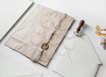 Vintage postal stationery with craft paper bag, wax seal, stamp and blank envelope on black paper background.